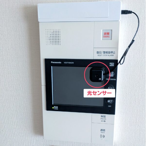 パナソニック製の集合住宅用インターホン室内親機。画面の右上に位置する黒い四角い「光センサー」が、赤丸と白い文字のラベルで強調されている。