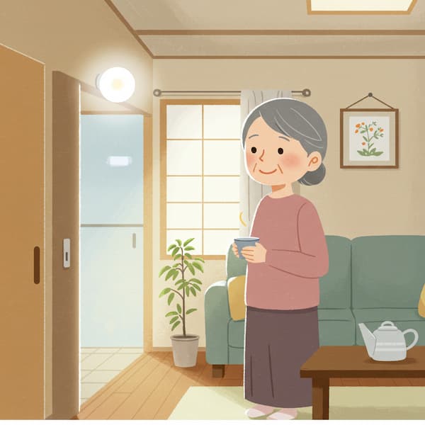 自宅のリビングで温かい飲み物の入ったカップを手に持ち、穏やかな表情で立っている高齢の女性。部屋のドアの上部には丸いLEDライトが光ってる