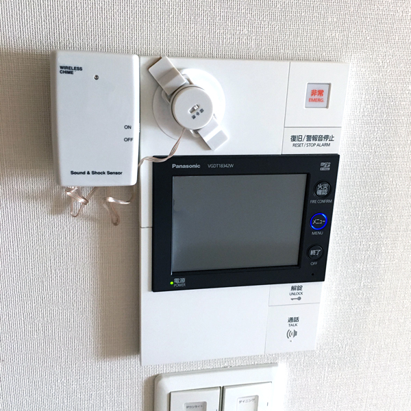 マンション用インターホン親機に音・振動センサーを取り付けた例。センサーが呼び出し音を感知する様子を示す。