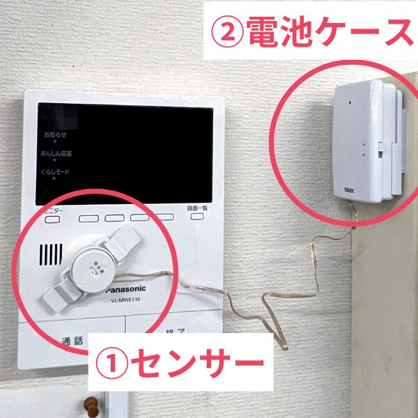 Panasonic製インターホンVL-MWE310の操作パネル横に円形センサーを取り付け、壁にはそのセンサーと線で繋がった白い電池ケースを固定した設置例。